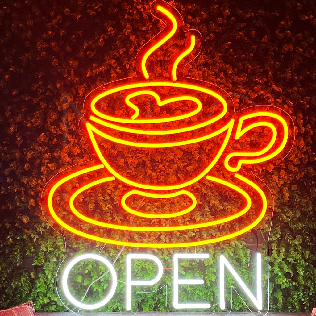 Neon sign of a coffee cup with steam and 'OPEN' text on a dark background.